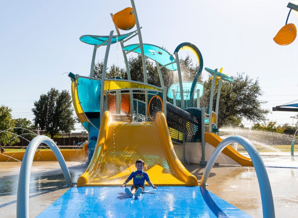 child sliding down large water play feature